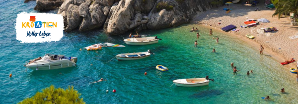 Blick auf einen kleinen Strand mit Menschen und Booten im Wasser.
